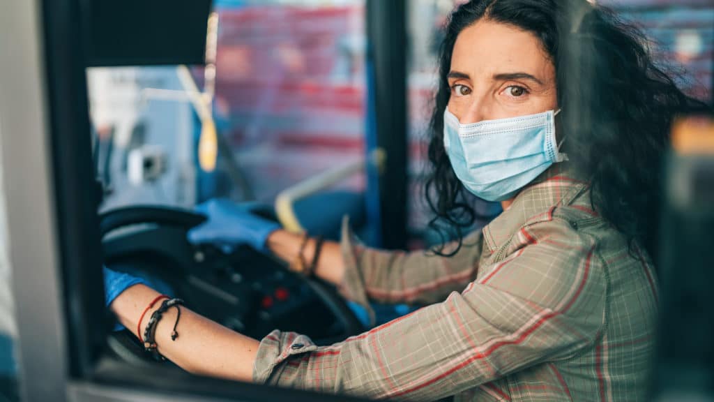 Female bus driver with protective mask working during COVID-19