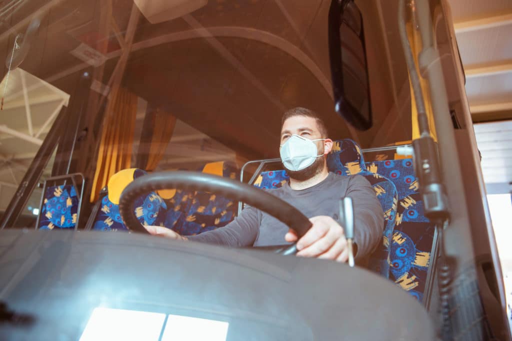 Professional bus driver in white protective suit wearing mask